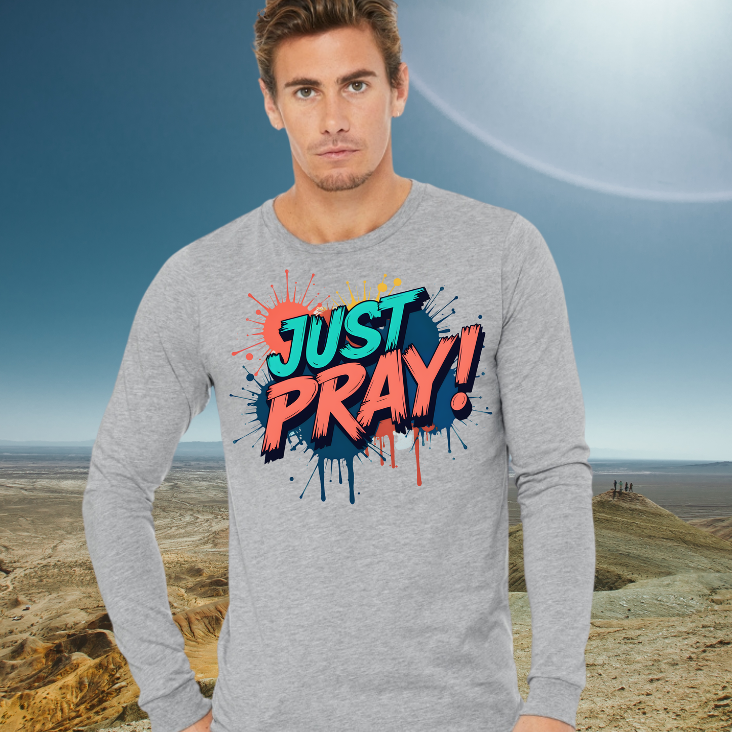 Man wearing a gray long-sleeve shirt with 'JUST PRAY!' text in colorful letters against a desert landscape.