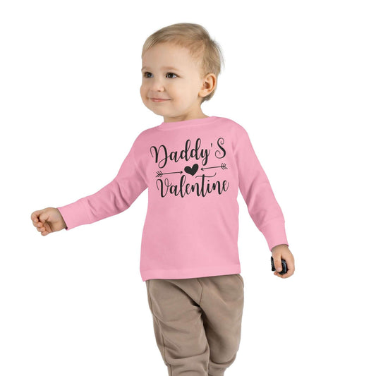 Toddler wearing a pink long sleeve tee with the text 'Daddy's Valentine' in a playful design.