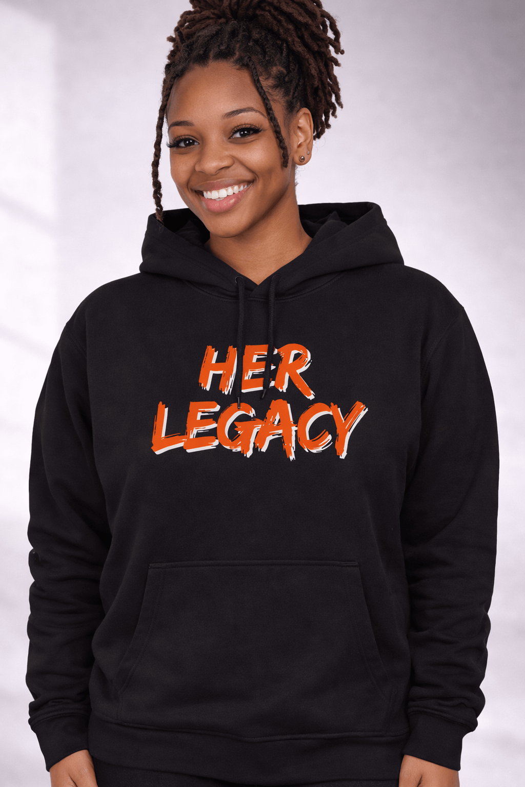 Model wearing HER LEGACY hoodie in black with vibrant orange lettering, showcasing comfort and style.