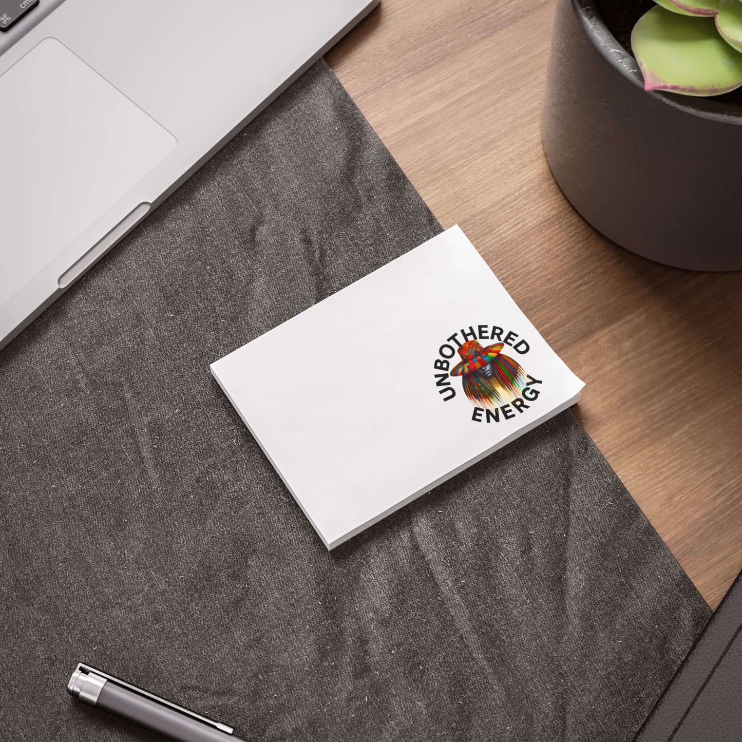 Unbothered Energy Post-it Note Pads on a workspace with a laptop and plant, featuring cheerful design.